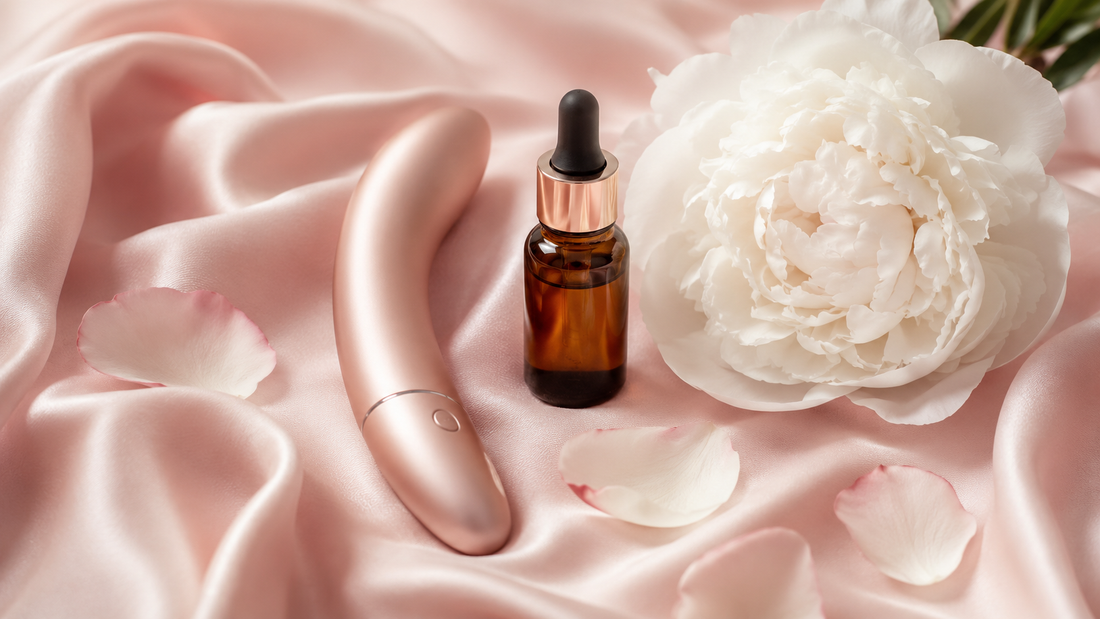 Flat lay élégant de bien-être intime avec stimulateur or rose, huile intime et pivoine blanche sur satin rose.